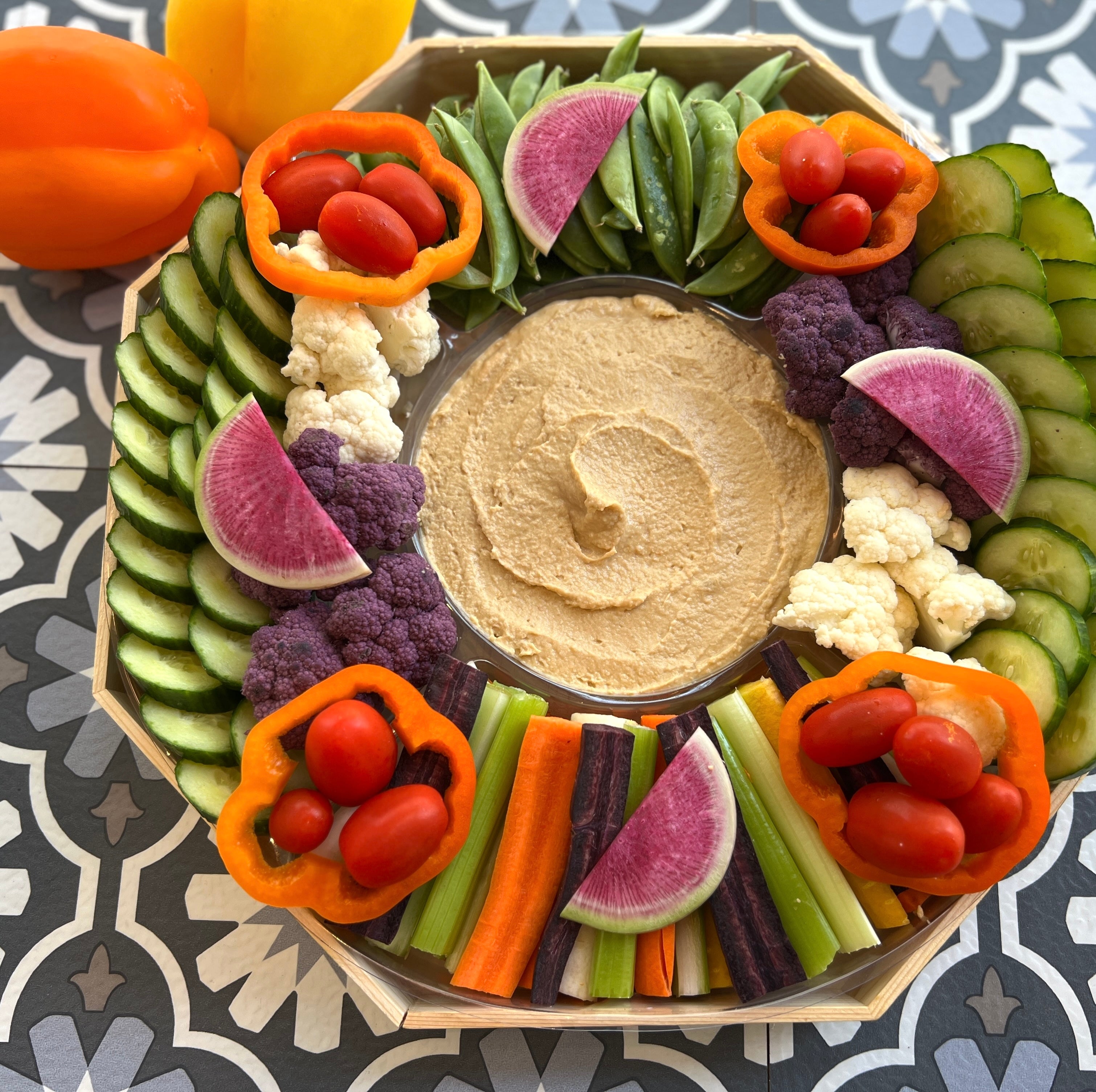 Our signature crudite platter with rainbow carrots, celery, snap peas, cucmbers, cauliflower, grape tomatoes and hummus dip in the center.