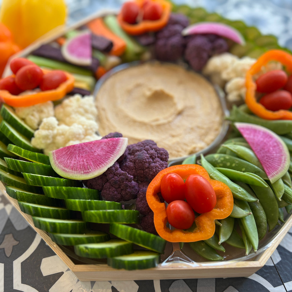 Our signature crudite platter with rainbow carrots, celery, snap peas, cucmbers, cauliflower, grape tomatoes and hummus dip in the center.