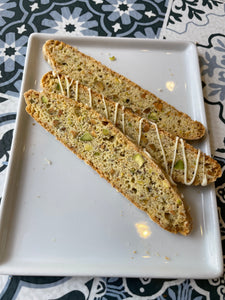 backside of pistachio lemon biscotti, showing chunks in the bread, 3 pieces displayed on a white plate.