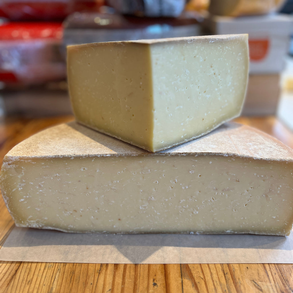 half wheel of cheese, with quarter wheel on top. Yellow paste, hard rind, with white specks
