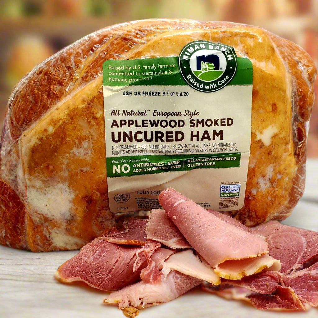 Close up of entire piece of ham in packaging with label plus some thick cut sliced folded in front.