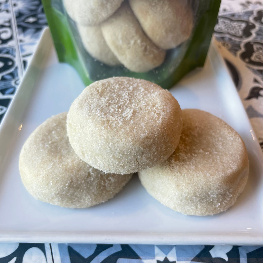 3 santa barbara shortbread brown butter cookies on a white plate, visible granular sugar ontop. half round cookies