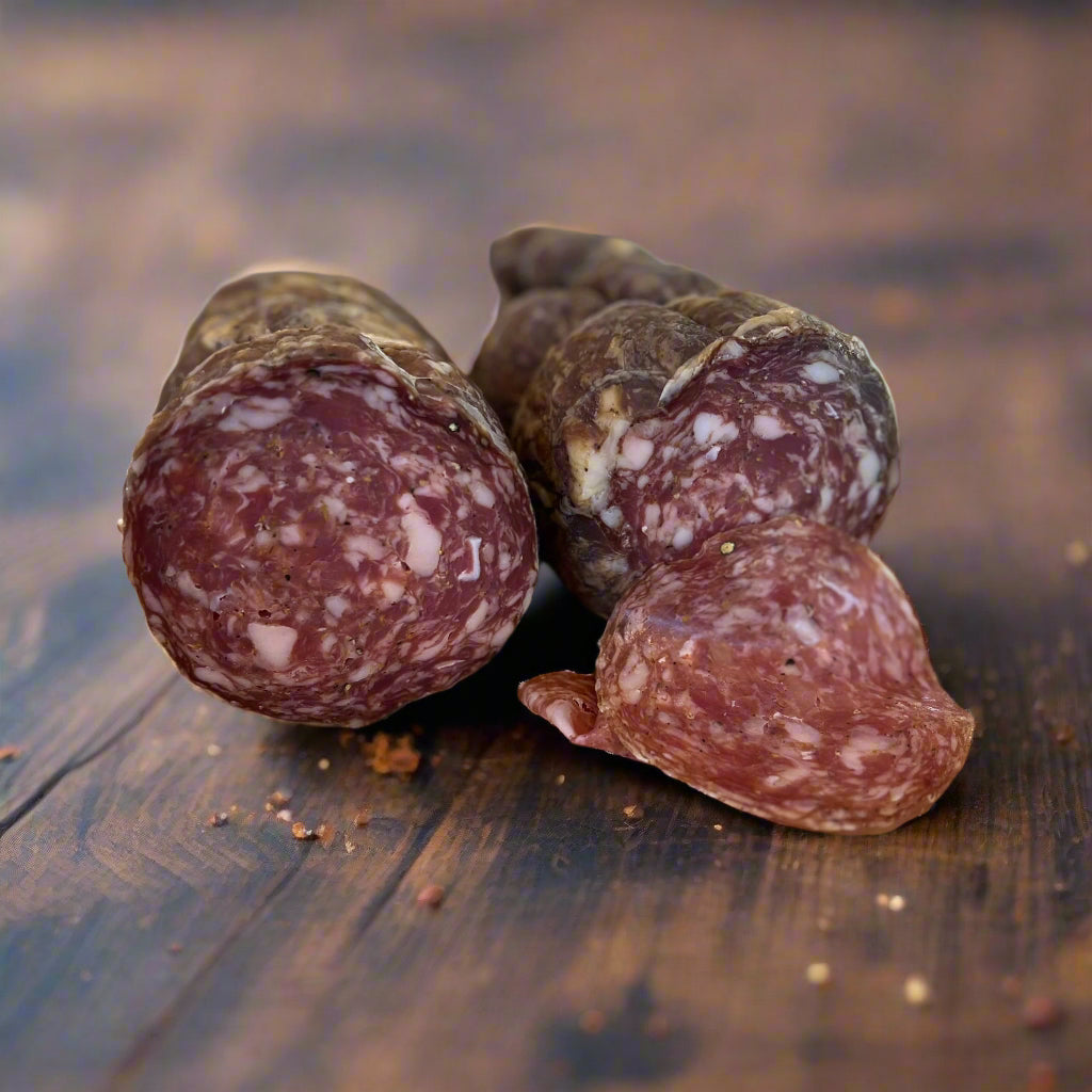 stick of Dodge City Salami by Smoking Goose, dark red salami, cut in half with faces showing and a couple thin slices in the foreground