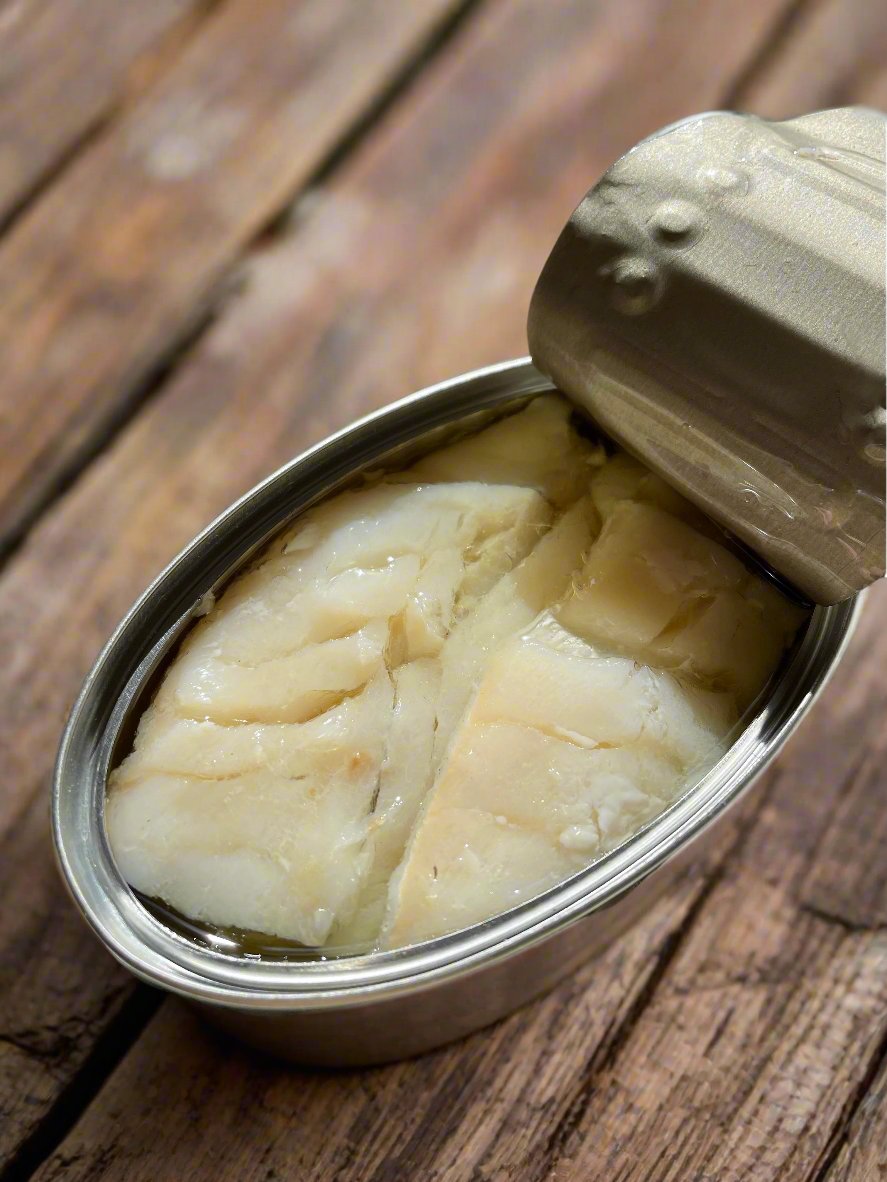 Opened tin of wild cod in spanish olive oil, on a wooden picnic bench