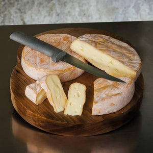 2 cheese wheels, with slices, with a knife atop, on a cutting board