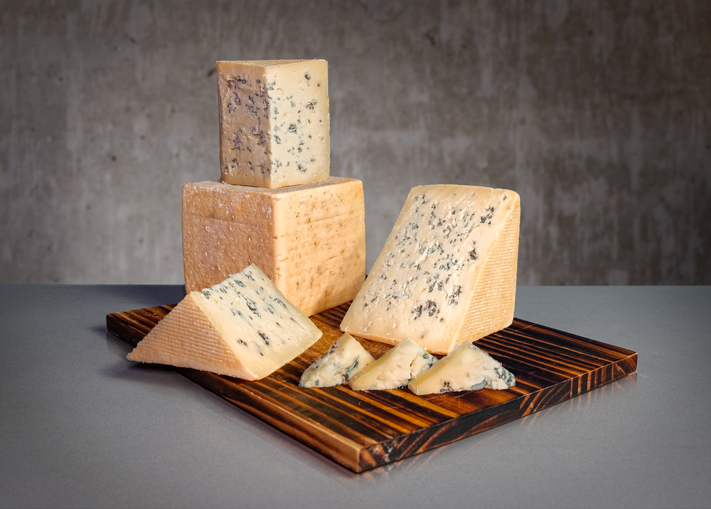 display arrangement of blue cheese of assorted shapes, on wooden butcher block