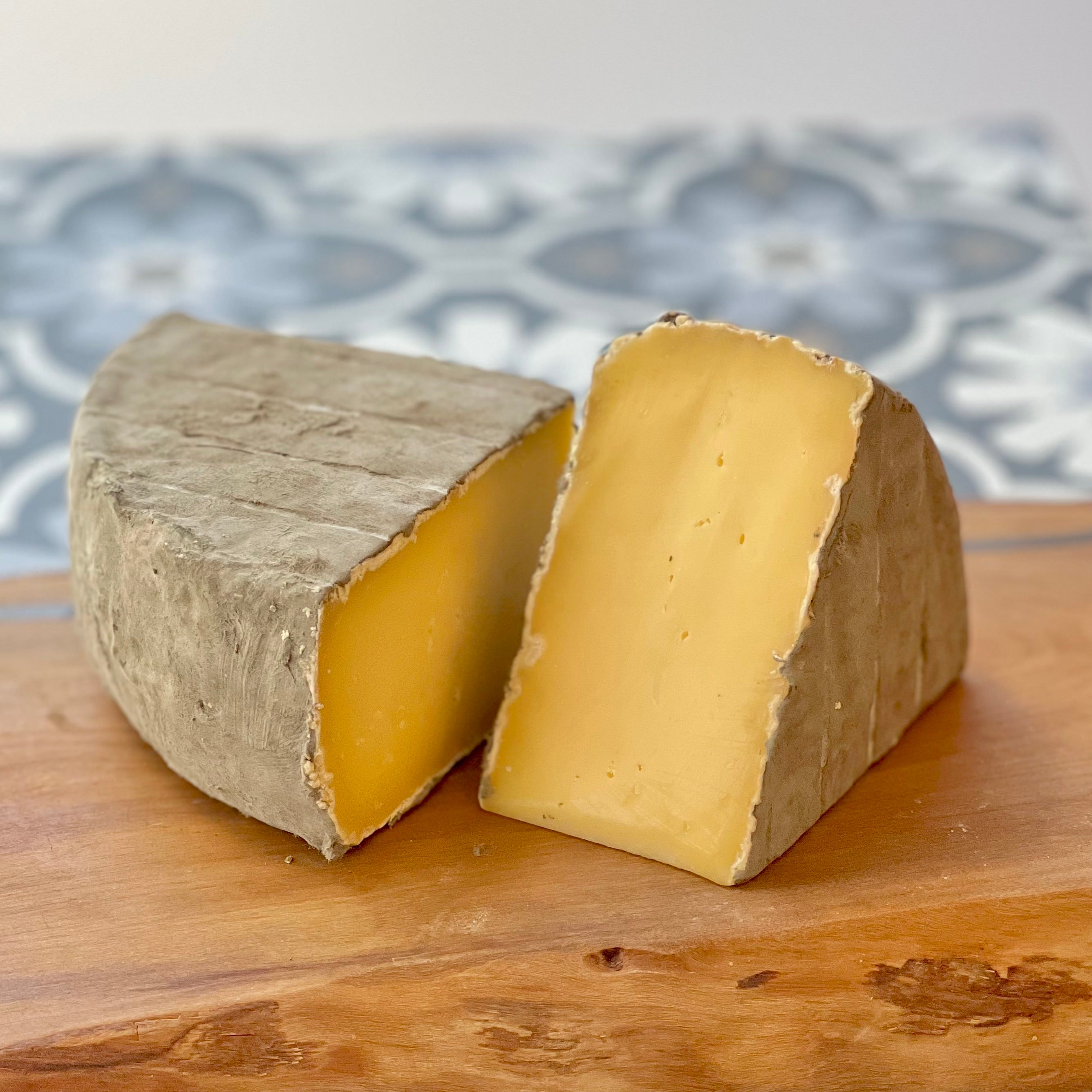 quarter cheese wheel, pale yellow cheese on it's side, on a wooden board